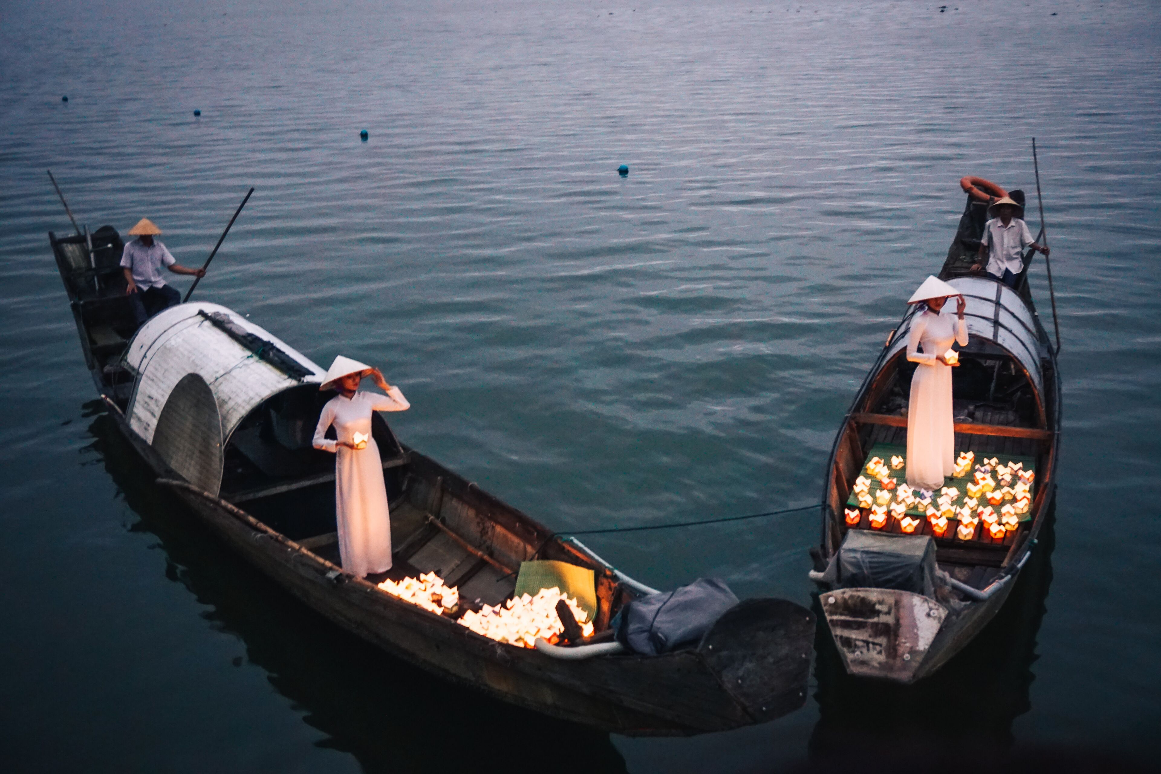 Two boats on calm water, each carrying a person and a load of goods.