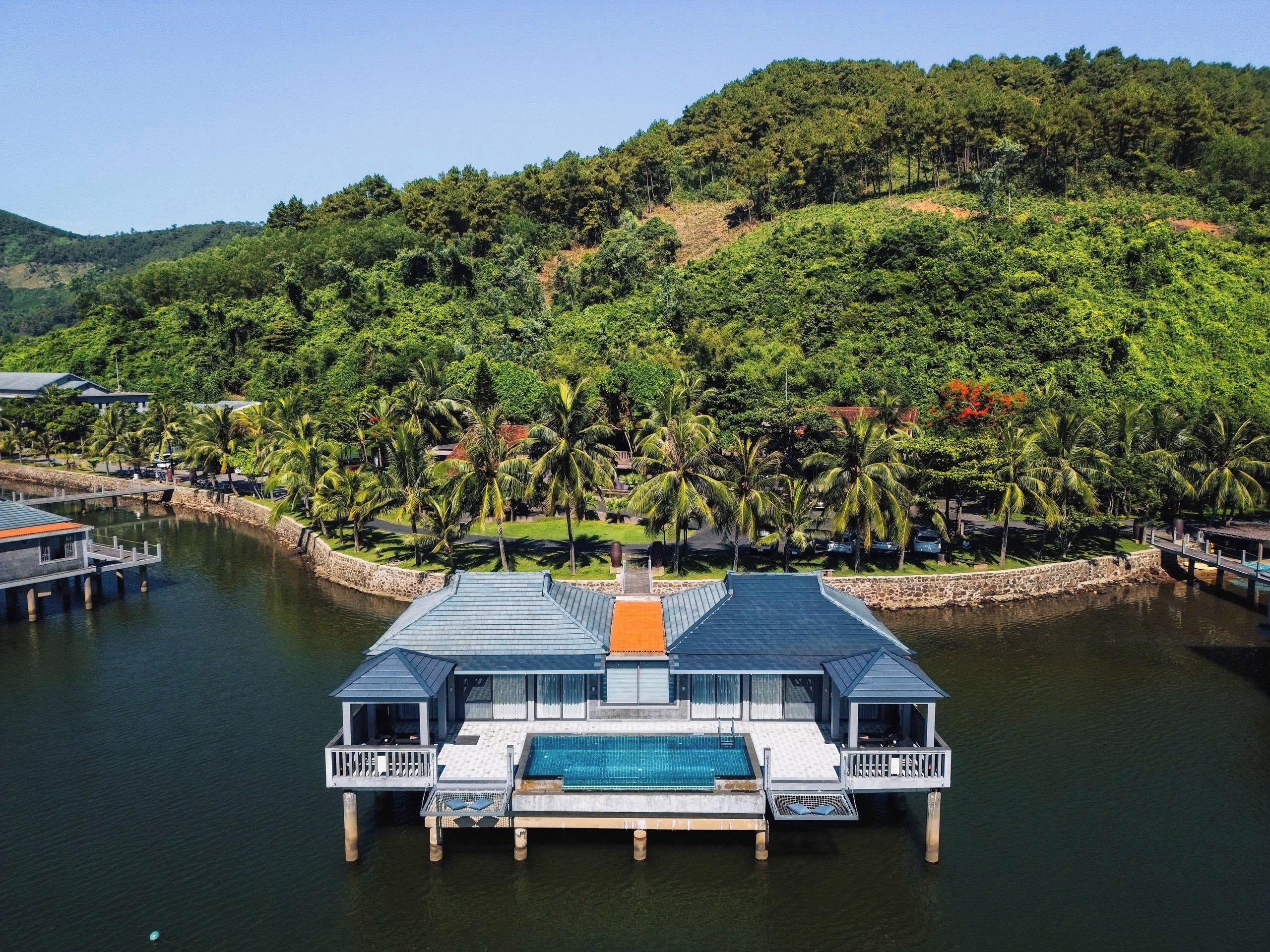 A waterfront property with a pool, dock, and lush greenery.
