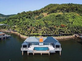 Una propiedad frente al agua con piscina, muelle y exuberante vegetación.