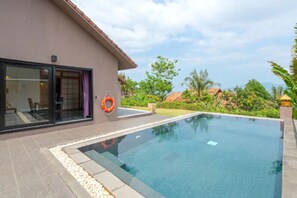 A modern pool area with a clear pool, a lifebuoy, and a glass door leading to a room. - Vedana Lagoon Resort and Spa (Hue)