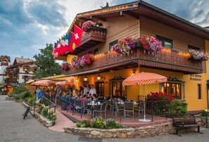 Ein Restaurant mit Außenbereich, einer Schweizer Flagge und Blumenkästen am Balkon.