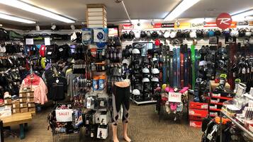 A ski equipment store with various helmets, goggles, and skis on display.