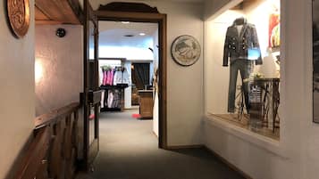 A corridor with a wooden railing, a clothing rack, and a mannequin in a window display.