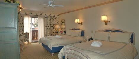 A hotel room with two beds, a ceiling fan, a balcony with curtains, and two wall-mounted lamps.