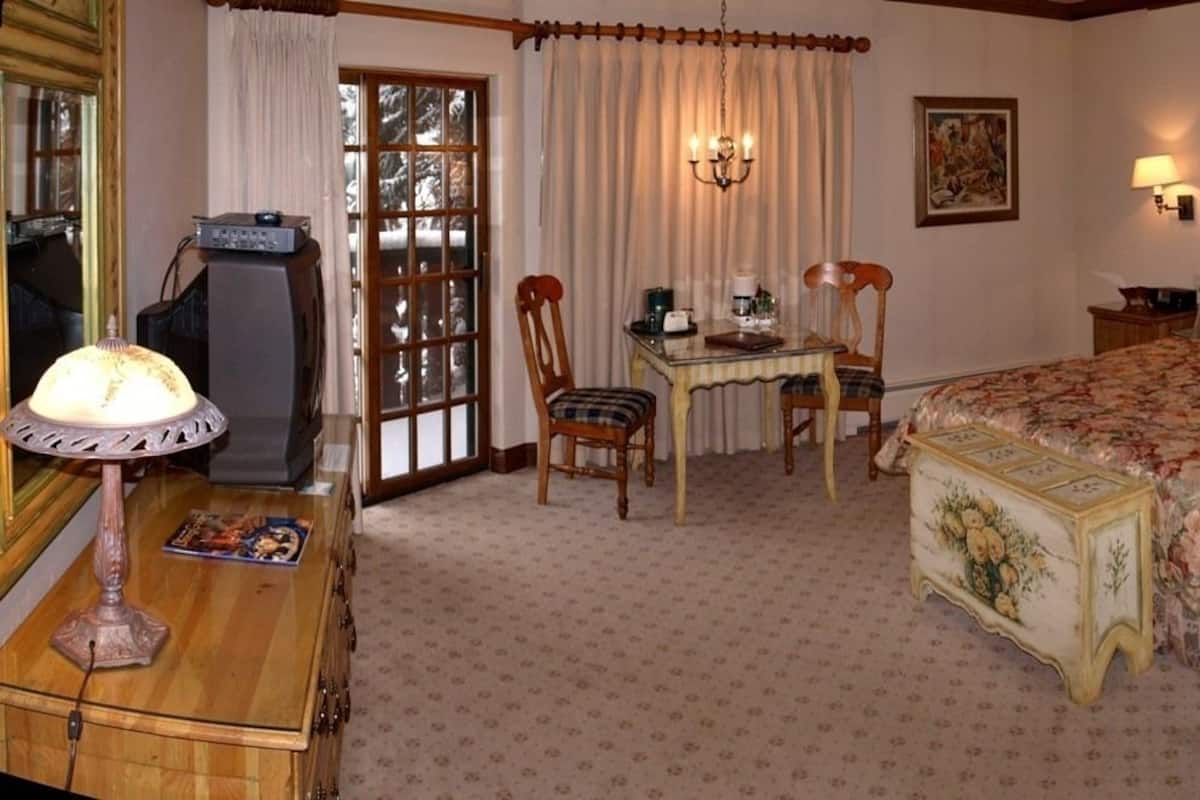 Een slaapkamer met een bed, een bureau, een stoel, een televisie en een lamp.