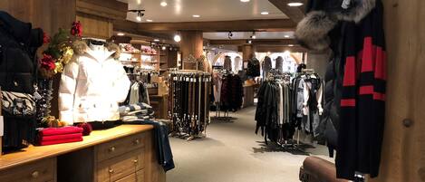 A clothing store with wooden interiors, racks of clothes, and a mannequin.