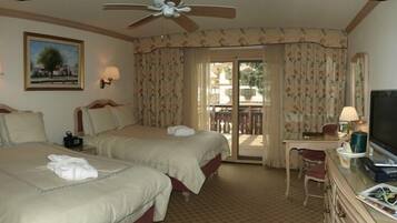 A hotel room with two beds, a desk with a computer, a TV, and a ceiling fan.