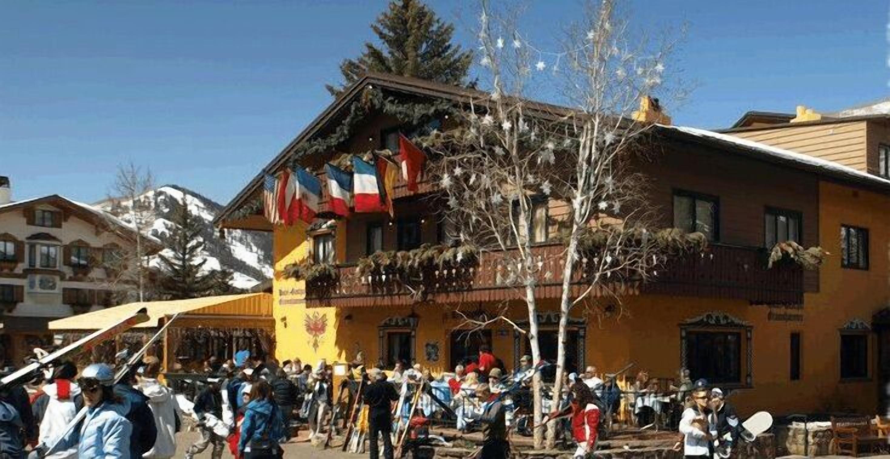 Un edificio con balcón adornado con banderas, una multitud de personas y montañas al fondo.