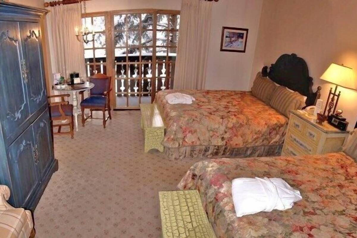 Een hotelkamer met twee bedden, een bureau, een stoel en een kledingkast.
