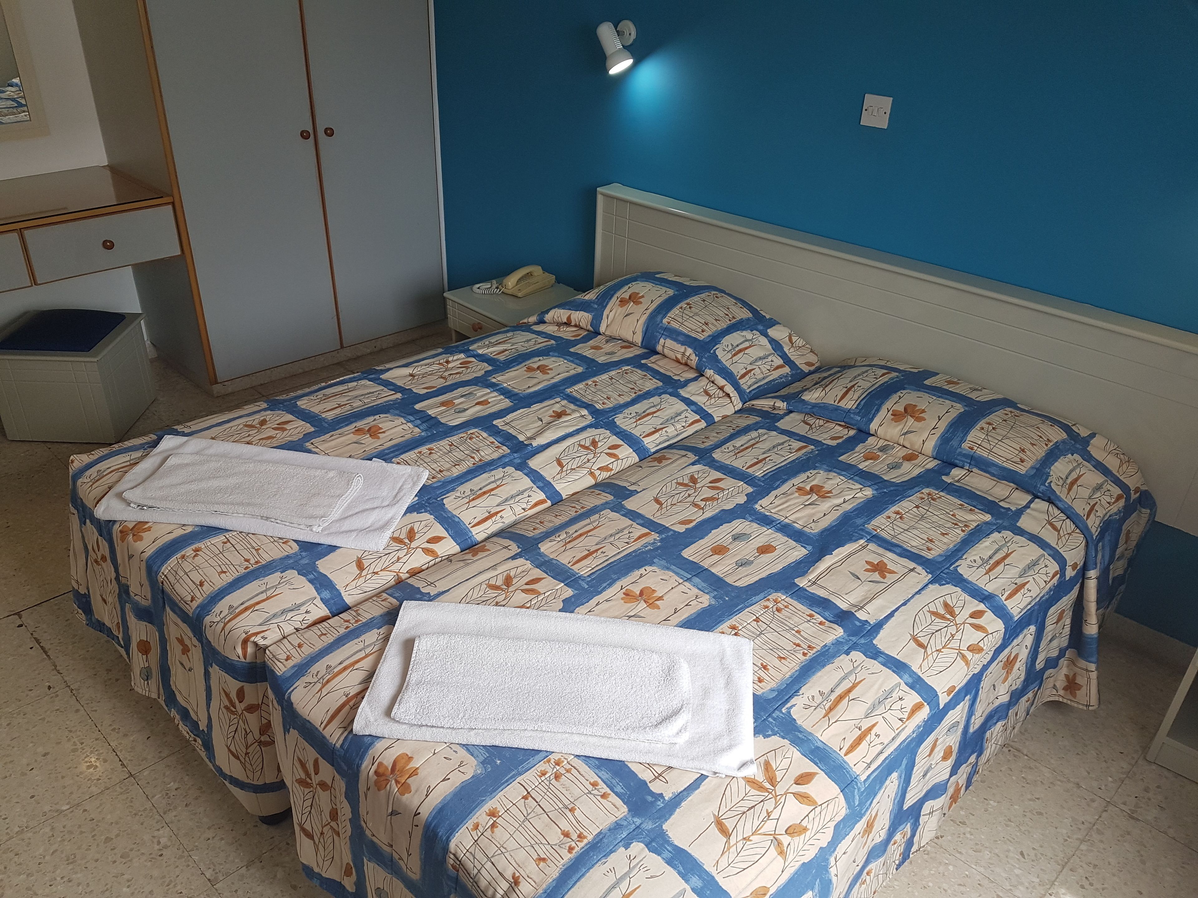 Una cama doble con una colcha de estampado floral y dos toallas blancas.
