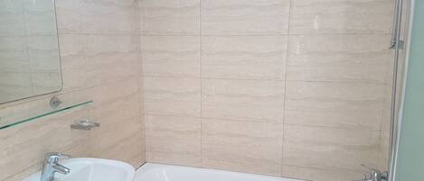 Un baño con lavabo, espejo y ducha.