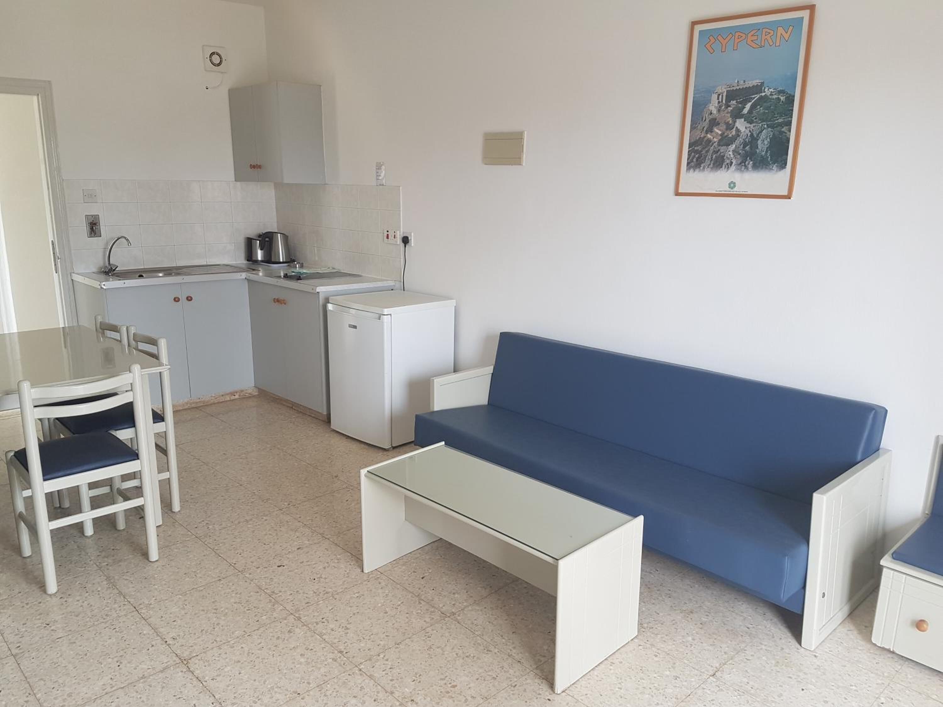 Een compacte keuken met een eethoek, inclusief een tafel, stoelen, een bank en een kleine koelkast.