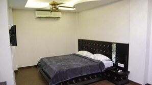 A bedroom with a bed, a nightstand, a ceiling fan, and an air conditioner. - Walnut Castle (New Delhi)