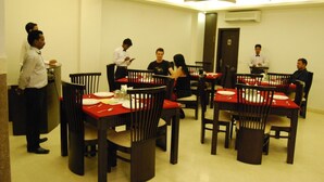 A dining area with tables set for four, each with red tablecloths and white plates. - Walnut Castle (New Delhi)