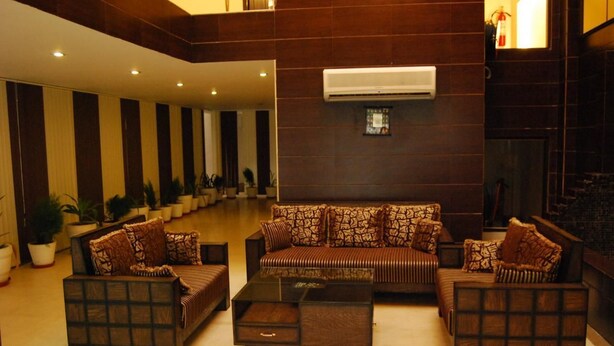 A spacious lobby with a central sofa set, a coffee table, and potted plants. - Walnut Castle (New Delhi)