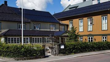 En traditionell byggnad med ett mörkt tak täckt med takpannor och en träfasad, med flera fönster och en tydligt synlig entré.