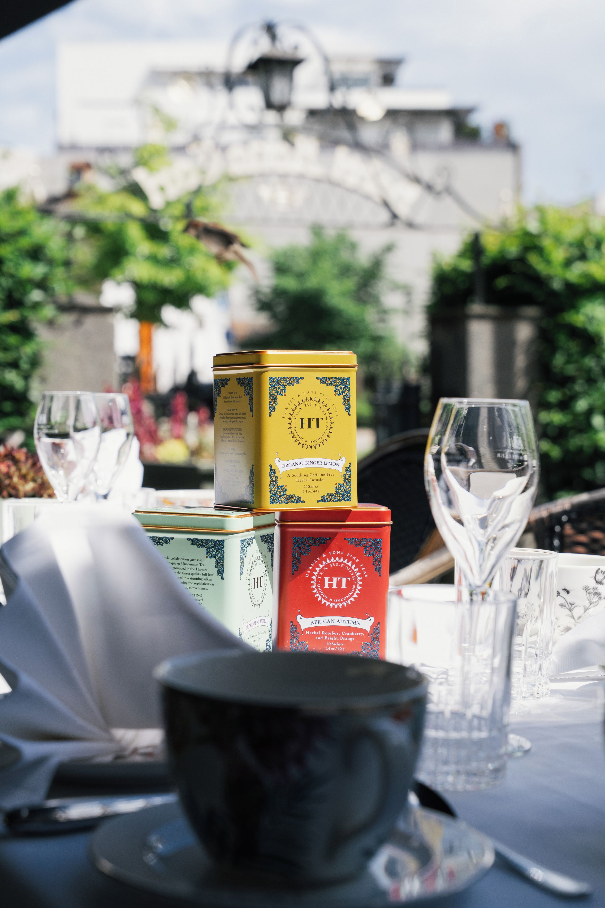 A table set with tea tins and glasses, with a building in the background.