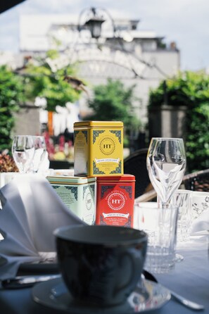 Una mesa dispuesta con latas de té y vasos, con un edificio al fondo.