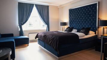 Un dormitorio moderno con una cama grande, una mesita de noche, una silla y una ventana con cortinas.