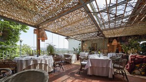 An outdoor dining area with tables and chairs, covered by a woven canopy, and surrounded by greenery. - La Piconera And Spa (Ribadesella)