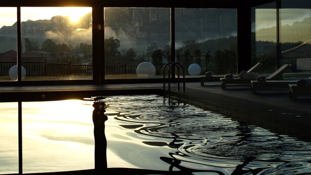 A pool area with a view of mountains and a sunset. - La Piconera And Spa (Ribadesella)