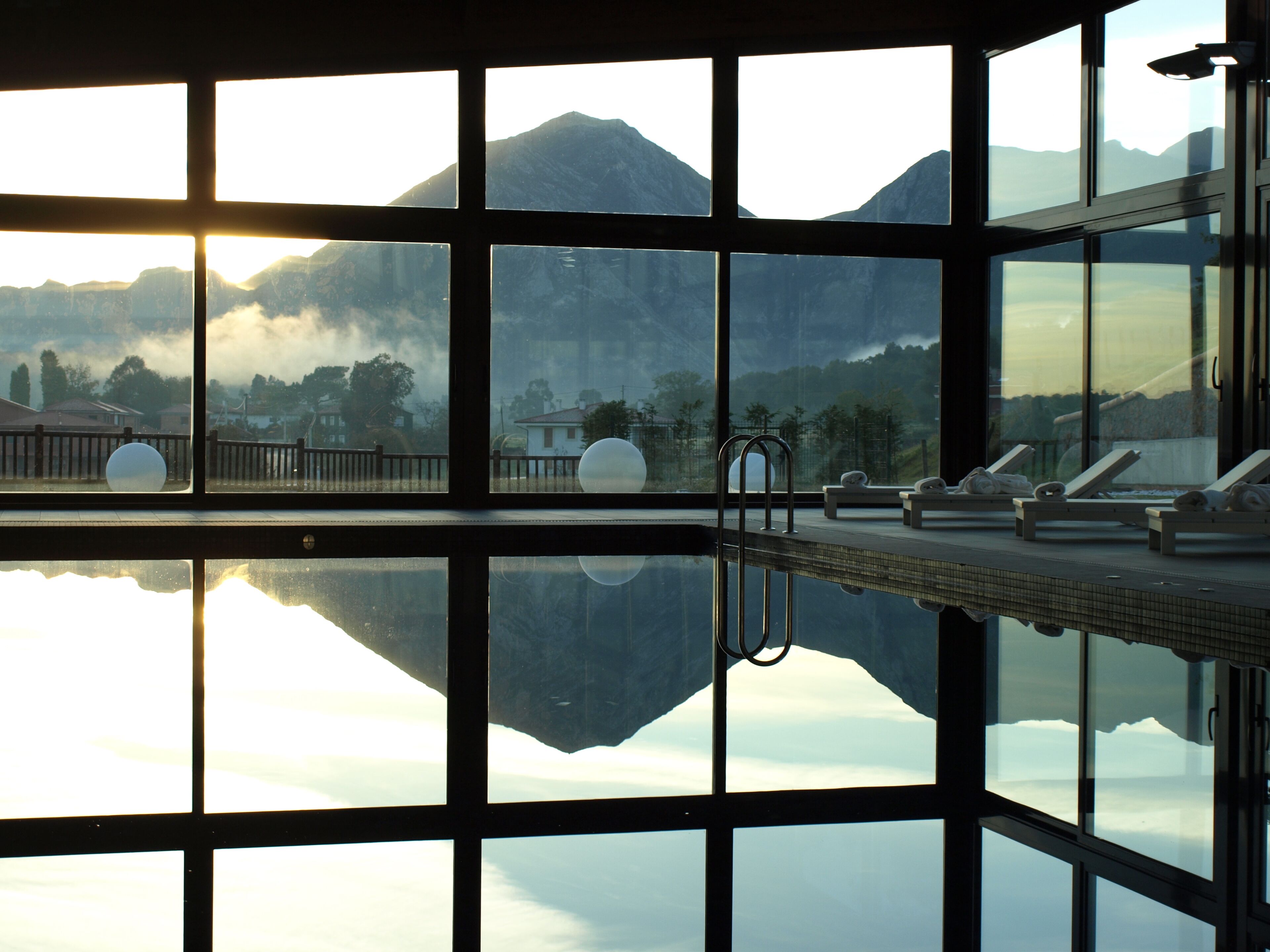 A swimming pool with a view of mountains through large windows.