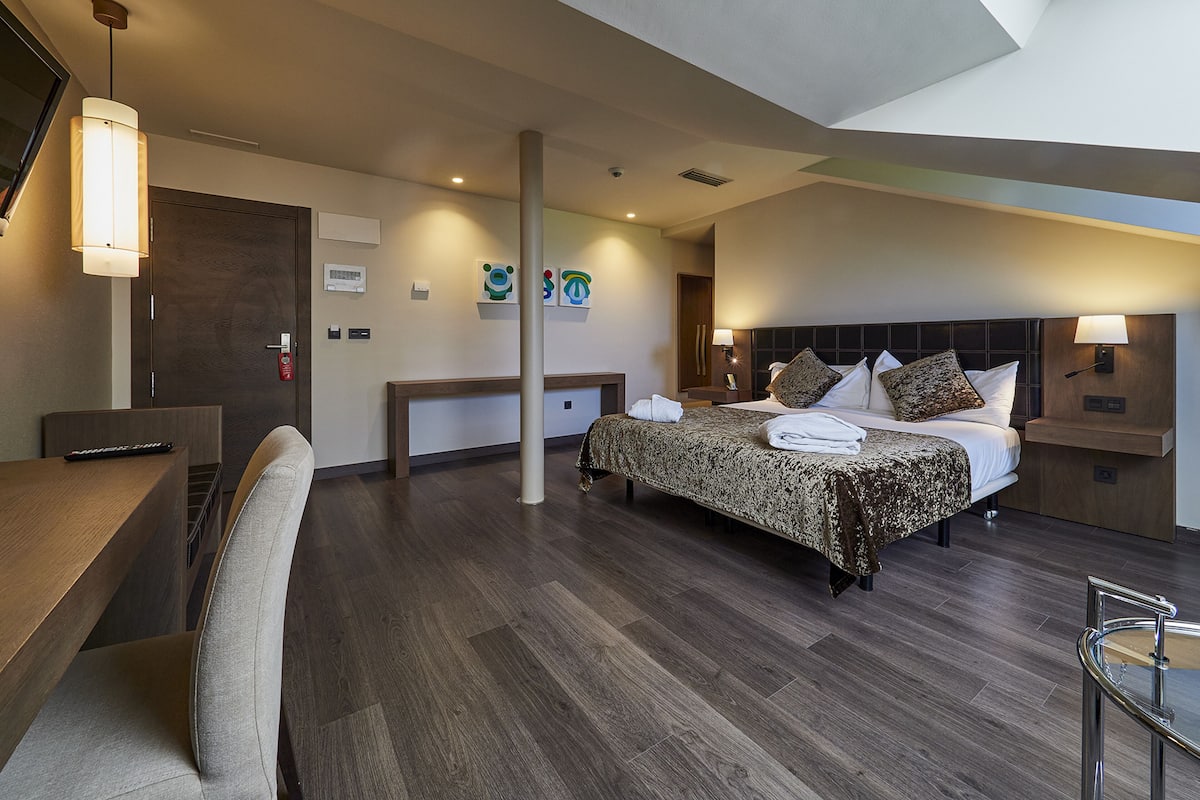 A modern hotel room with a large bed, a desk, and a chair.