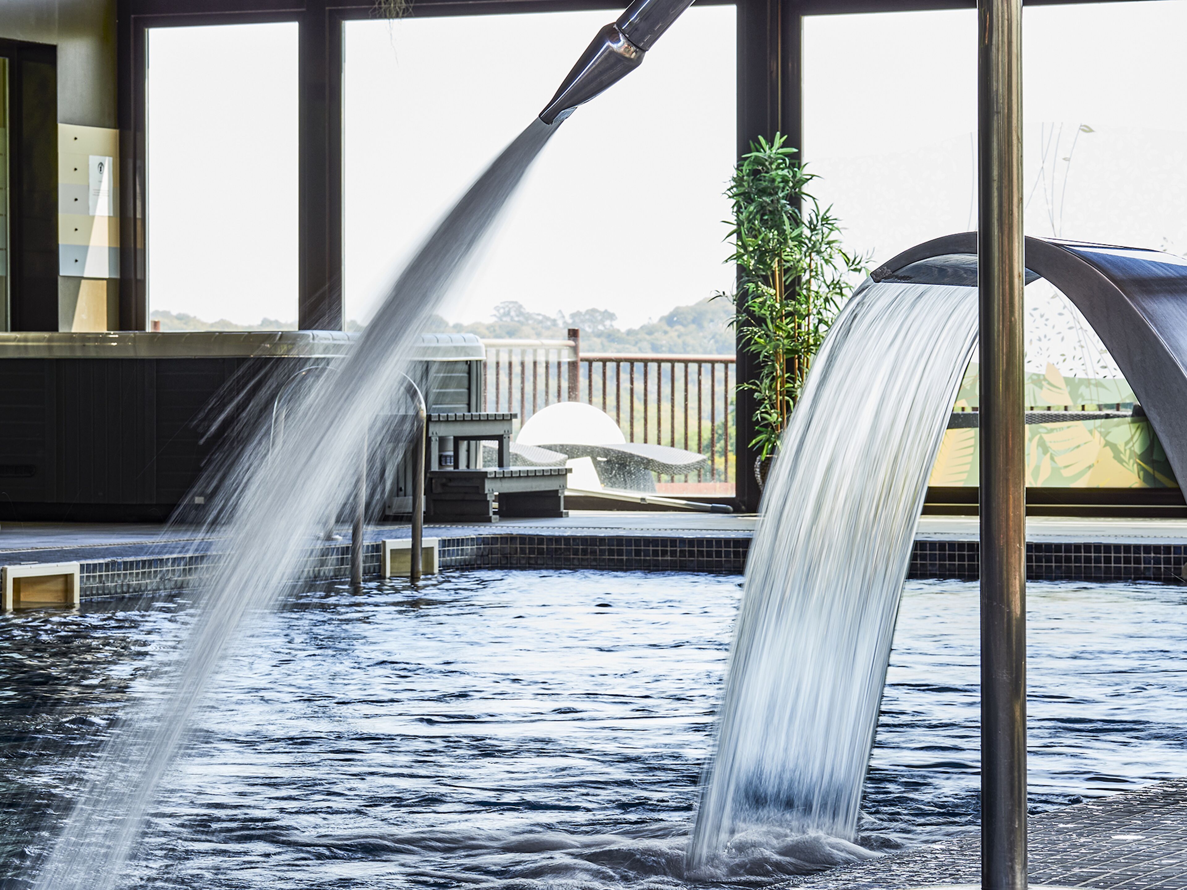 Een bubbelbad met waterstralen, een houten terras en een bloempot.