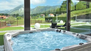 A hot tub with a mountain view, surrounded by a deck and a fence. - La Piconera And Spa (Ribadesella)