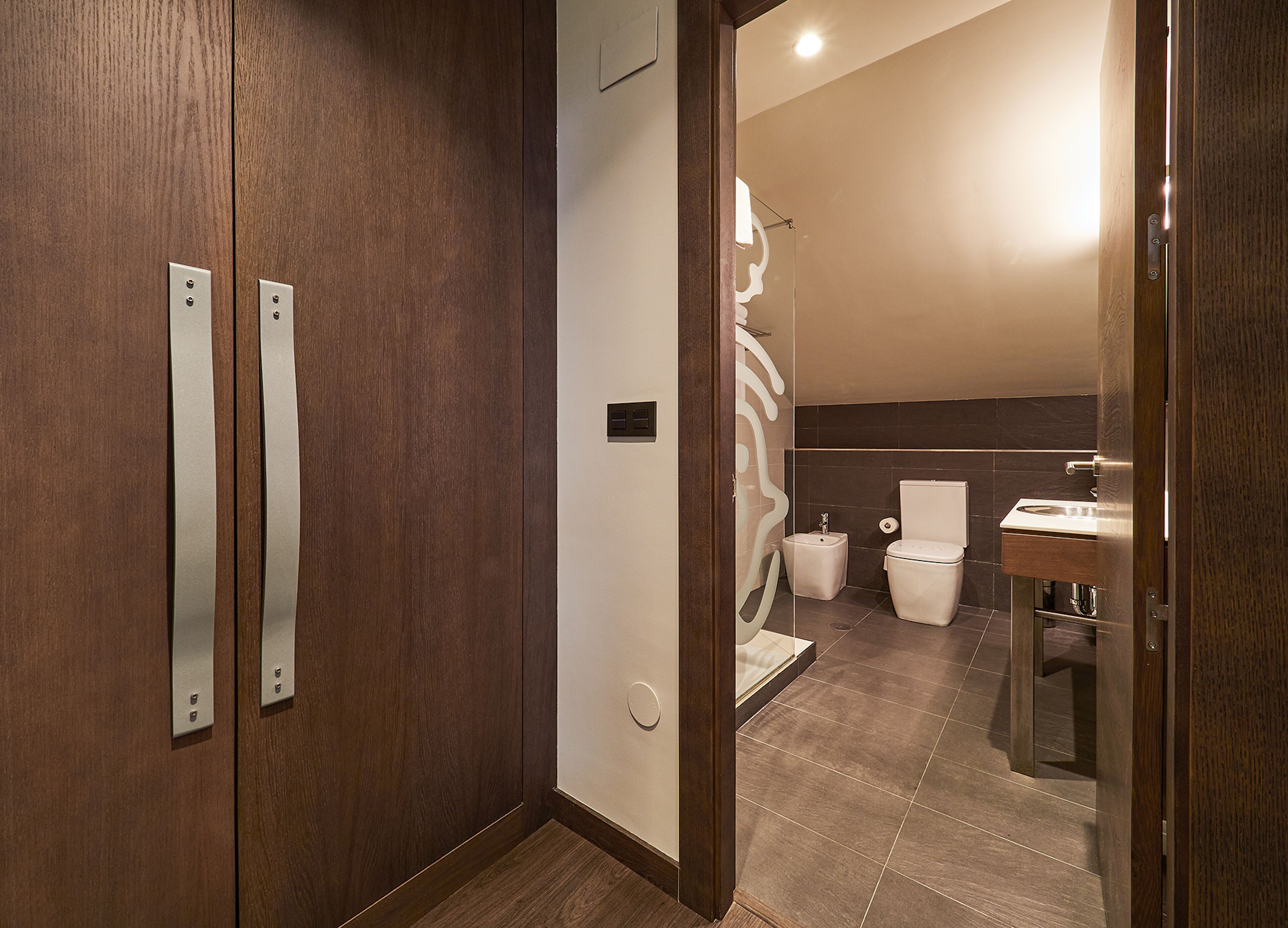 A modern bathroom with a wooden vanity, a toilet, and a sink.