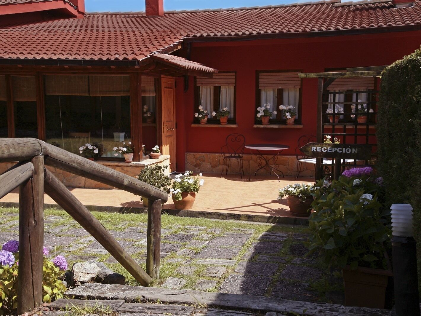 Un edificio rojo con tejado de tejas, zona de recepción y mesas al aire libre.