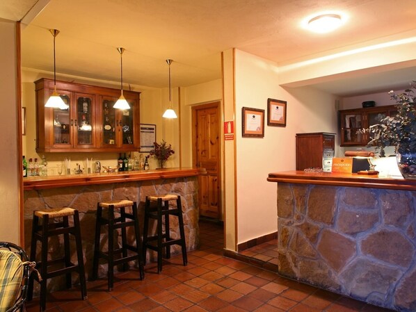 A bar area with stone counter, wooden stools, and hanging pendant lights. - Hotel Casa Camila (Oviedo)