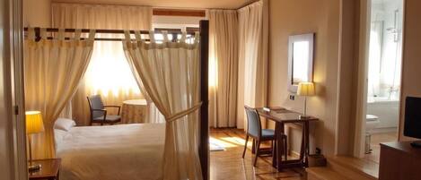A hotel room with a bed, a desk, a chair, a table, and a television.
