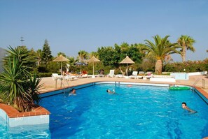 Alberca al aire libre, sombrillas en la alberca y camastros