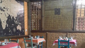 A restaurant with tables set for dining, featuring a rustic interior with wooden walls and a map on the wall. - Pousada da Terra Paraty (Paraty)