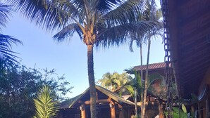 A tropical garden with a stone pathway leading to a wooden building with columns. - Pousada da Terra Paraty (Paraty)