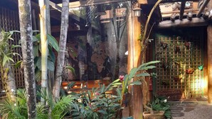 A rustic outdoor area with a wooden bench, potted plants, and a wall with a world map mural. - Pousada da Terra Paraty (Paraty)