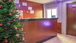 A reception desk with a Christmas tree, wooden paneling, and a clock on the wall. - Hotel Blanca Paloma (Las Palmas de Gran Canaria)