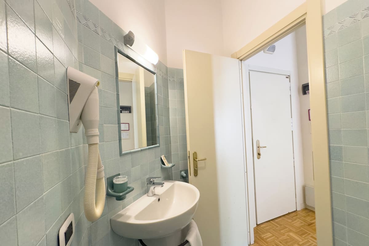 A bathroom with a sink, mirror, towel rack, and a door leading to another room.