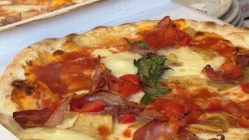 Eine Pizza mit Belag aus Speck, Käse und Tomaten.