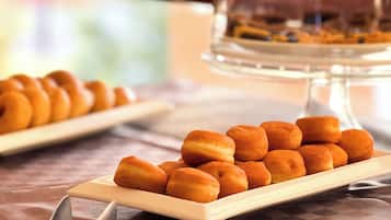 Una mesa de buffet con una variedad de pasteles y una vitrina en el fondo.