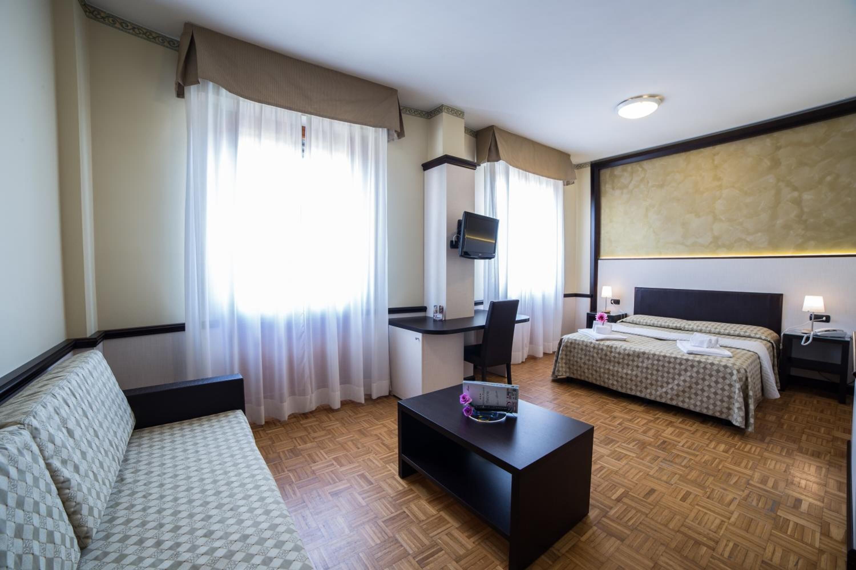Una habitación de hotel con sofá, escritorio, cama y televisor.