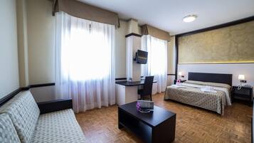 Una habitación de hotel con sofá, escritorio, cama y televisor.