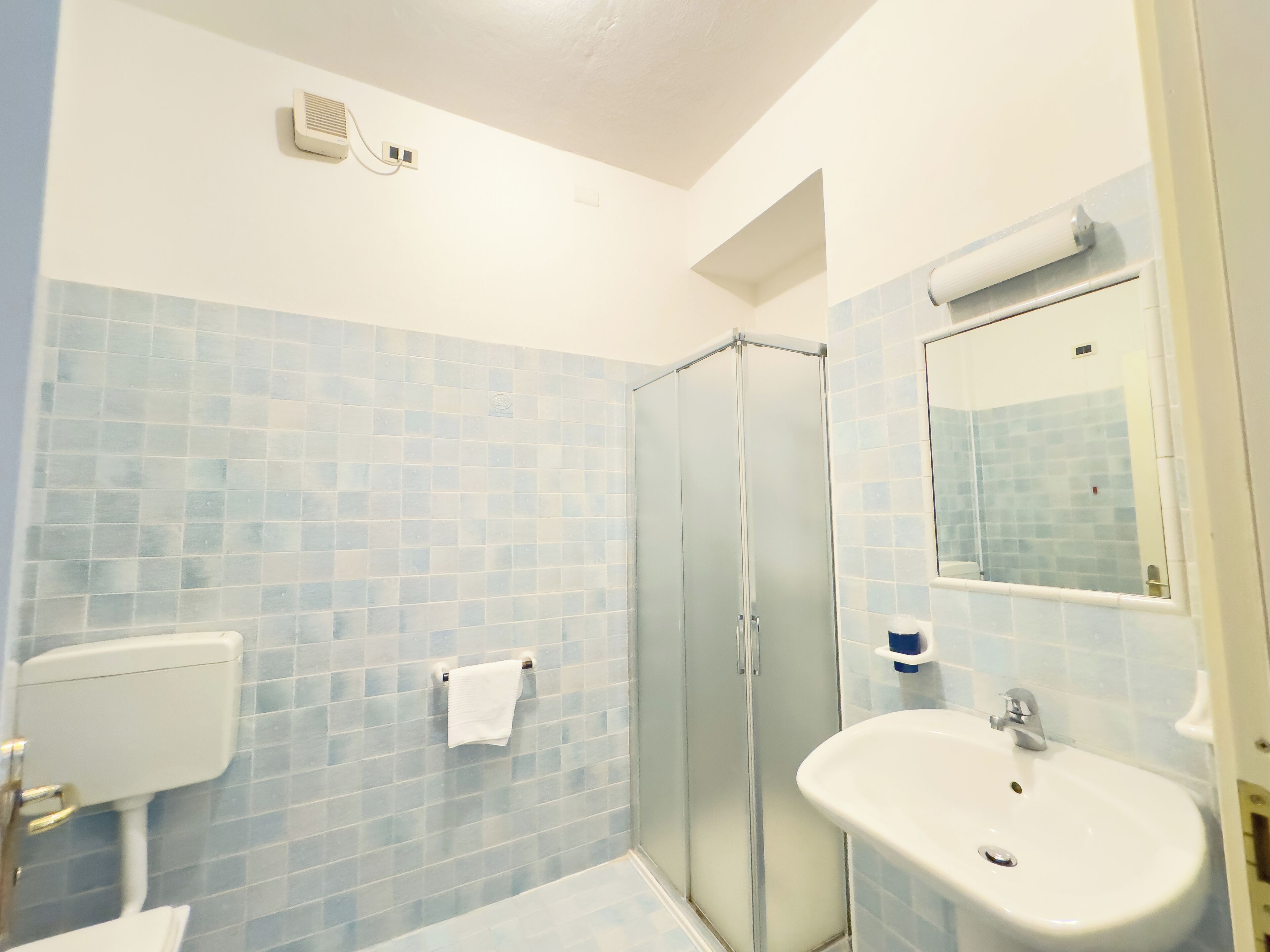 Ein Badezimmer mit Duschkabine aus Glas, einem weißen Waschbecken und einer Toilette.
