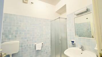 Ein Badezimmer mit Duschkabine aus Glas, einem weißen Waschbecken und einer Toilette.