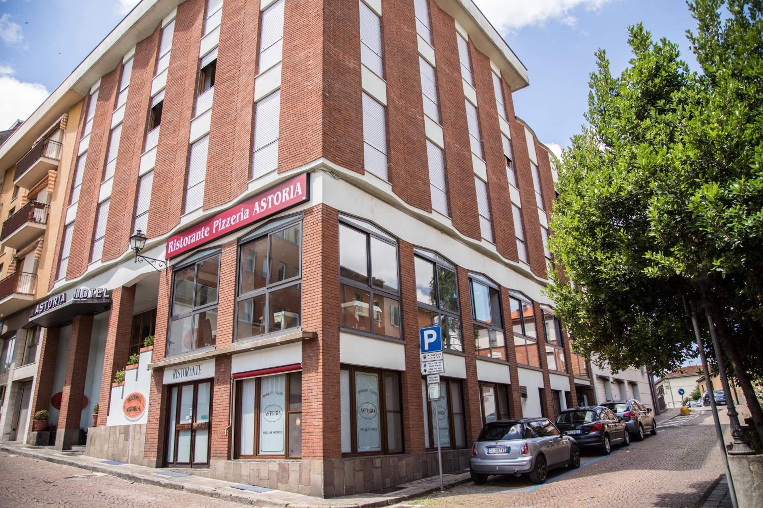 Un edifici amb un cartell de 'Ristorante Pizzeria Astoria' i un senyal de 'P' d'aparcament.