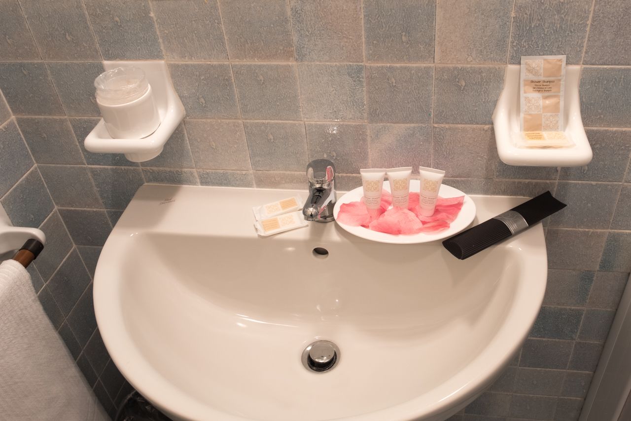 Ein Badezimmerwaschbecken mit Pflegeartikeln, einer Seifenspender und einem Handtuchhalter.