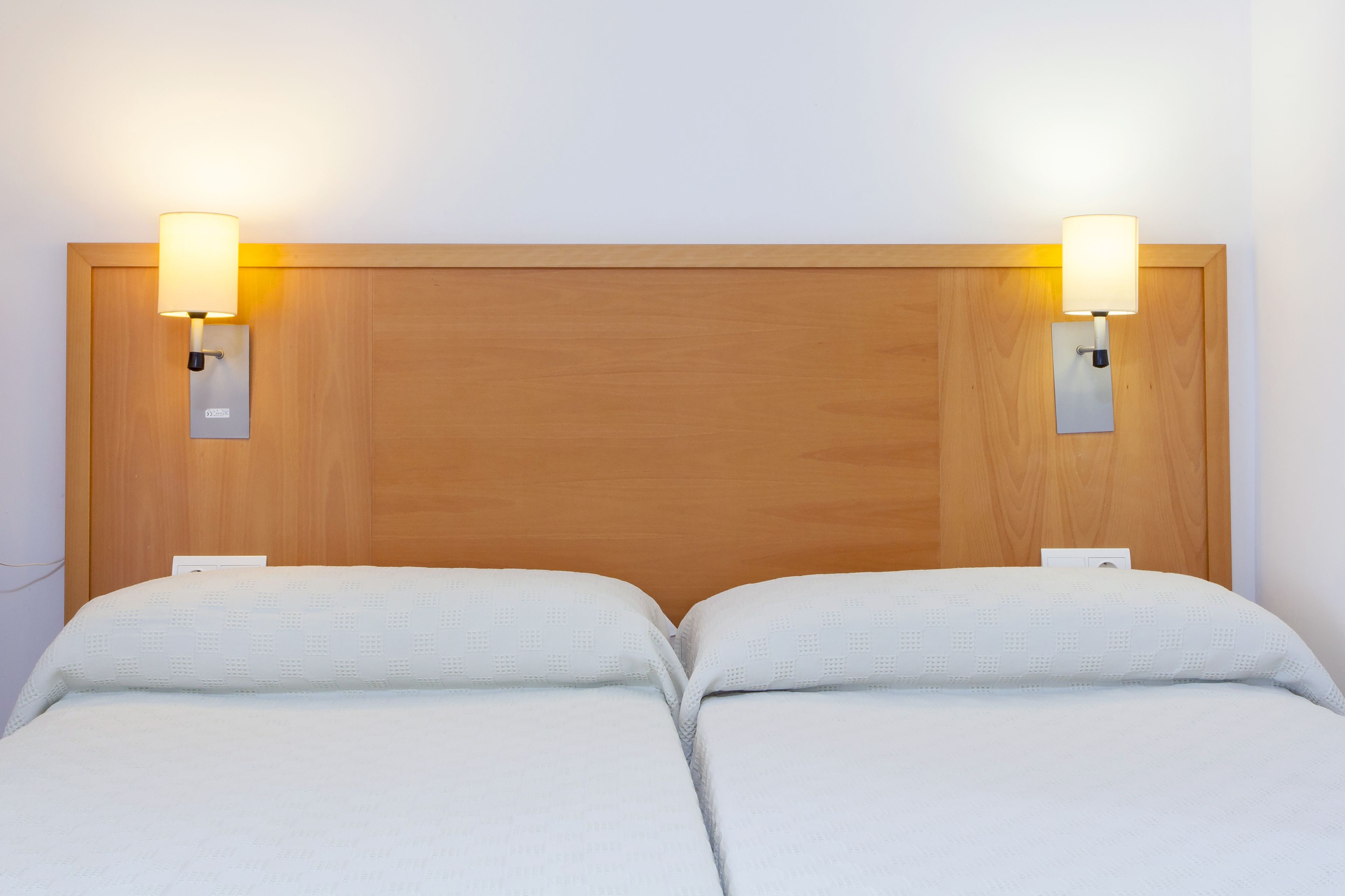 A double bed with two bedside tables, each with a wall-mounted lamp.