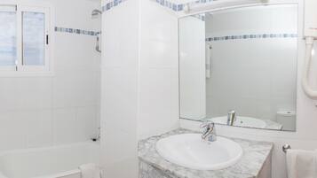 Un baño con bañera, lavabo con encimera de mármol y ducha con puerta de cristal.