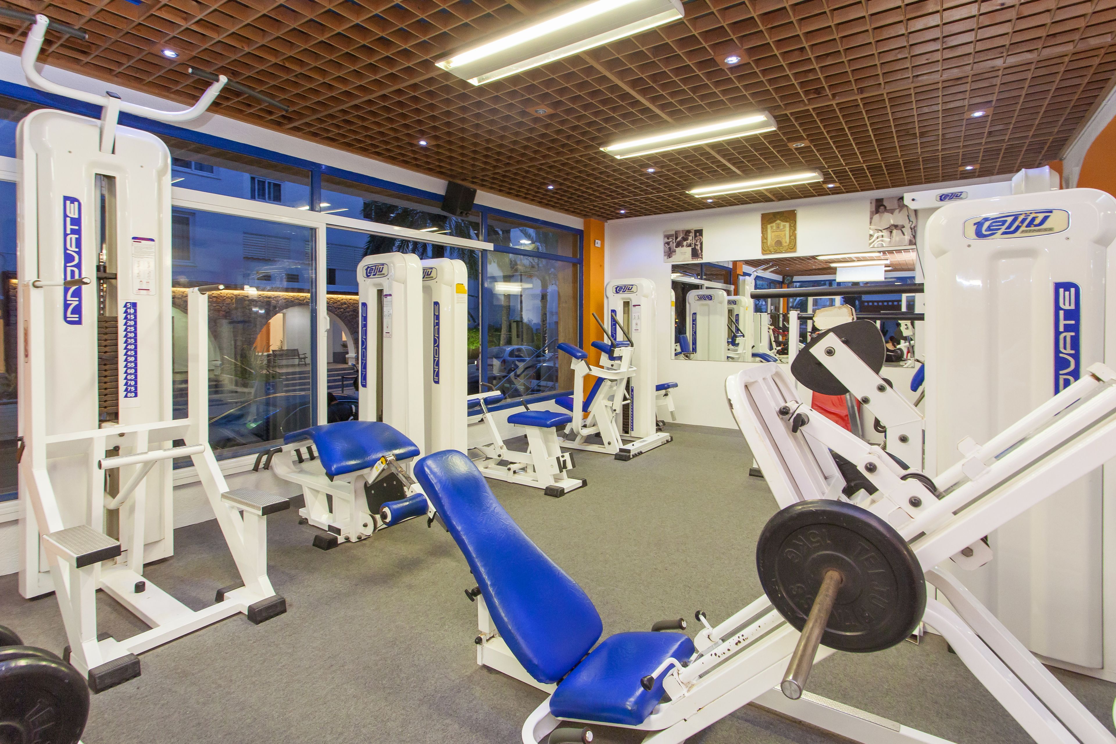 Un gimnasio con varias máquinas de ejercicio, incluyendo una prensa de banca y una prensa de piernas.